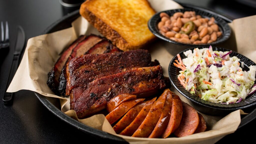 Plate of food from Big Jake's BBQ in Texarkana, Arkansas, with sausace, brisket, ribs, beans, coleslaw, and toast.