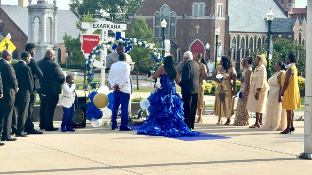 Wedding ceremony on State Line Avenue with guests split between Arkansas and Texas in Texarkana, Arkansas