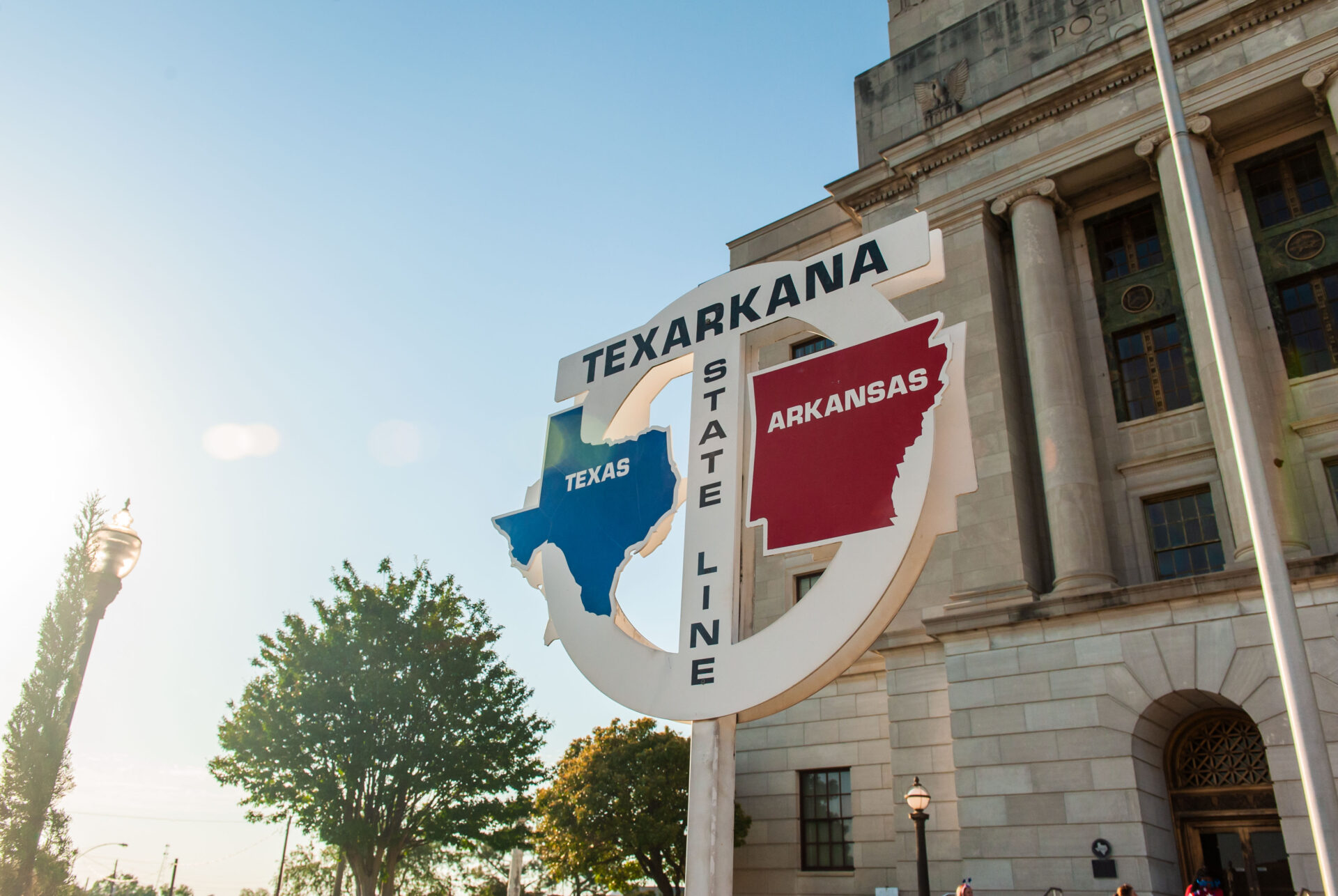 Texarkana state line sign showing Texas and Arkansas in front of the historic courthouse building.