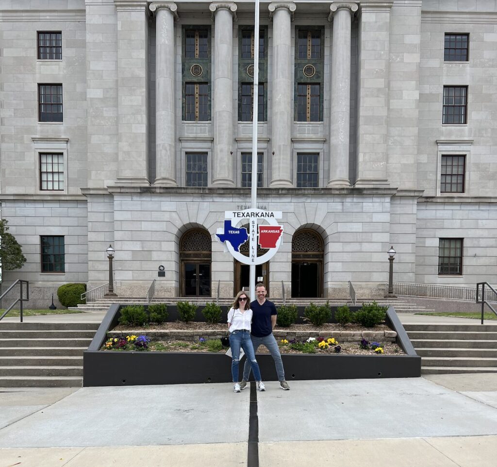 Visitors standing on the Texas–Arkansas state line in front of the Texarkana Post Office and Federal Building.