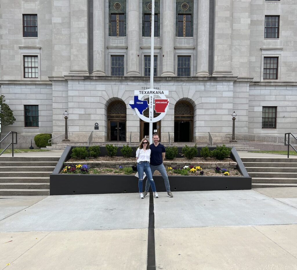 Visitors standing on the Texas–Arkansas state line in front of the Texarkana Post Office and Federal Building.