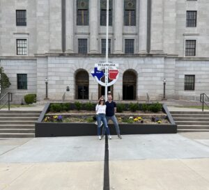 Visitors standing on the Texas–Arkansas state line in front of the Texarkana Post Office and Federal Building.