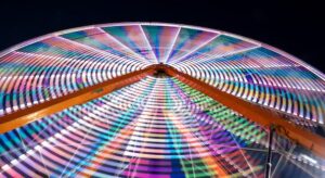 Colorful Ferris wheel light trails spinning at night carnival.